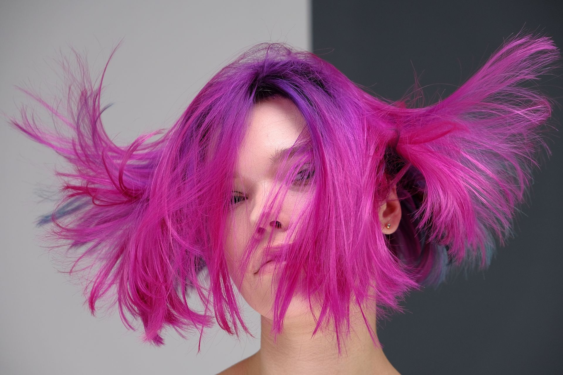 Concept Portrait of a punk girl, young woman with chic purple hair color in studio close up on a colorful background with fluttering hair. Short hairstyle, fashion haircut.